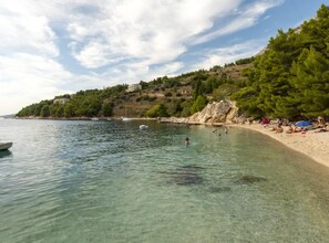 A beach with clear water, people swimming, and boats. - Comfort One Bedroom Apartment with Sea View and Terrace (Stanici)