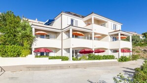 Een meerlaags hotel met balkons en rode parasols.