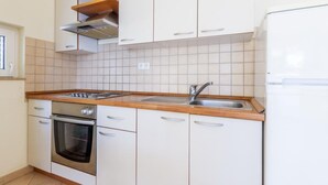 Eine Küche mit weißen Schränken, einem Edelstahlbackofen, einer Spüle und einer Holzarbeitsplatte.