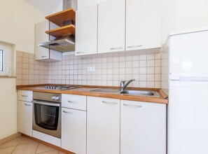 A kitchen with white cabinets, a stainless steel oven, a sink, and a wooden countertop. - Superior Two Bedroom Apartment with Sea View and Terrace (Stanici)