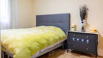 Een slaapkamer met een bed, een nachtkastje en een wandlamp.