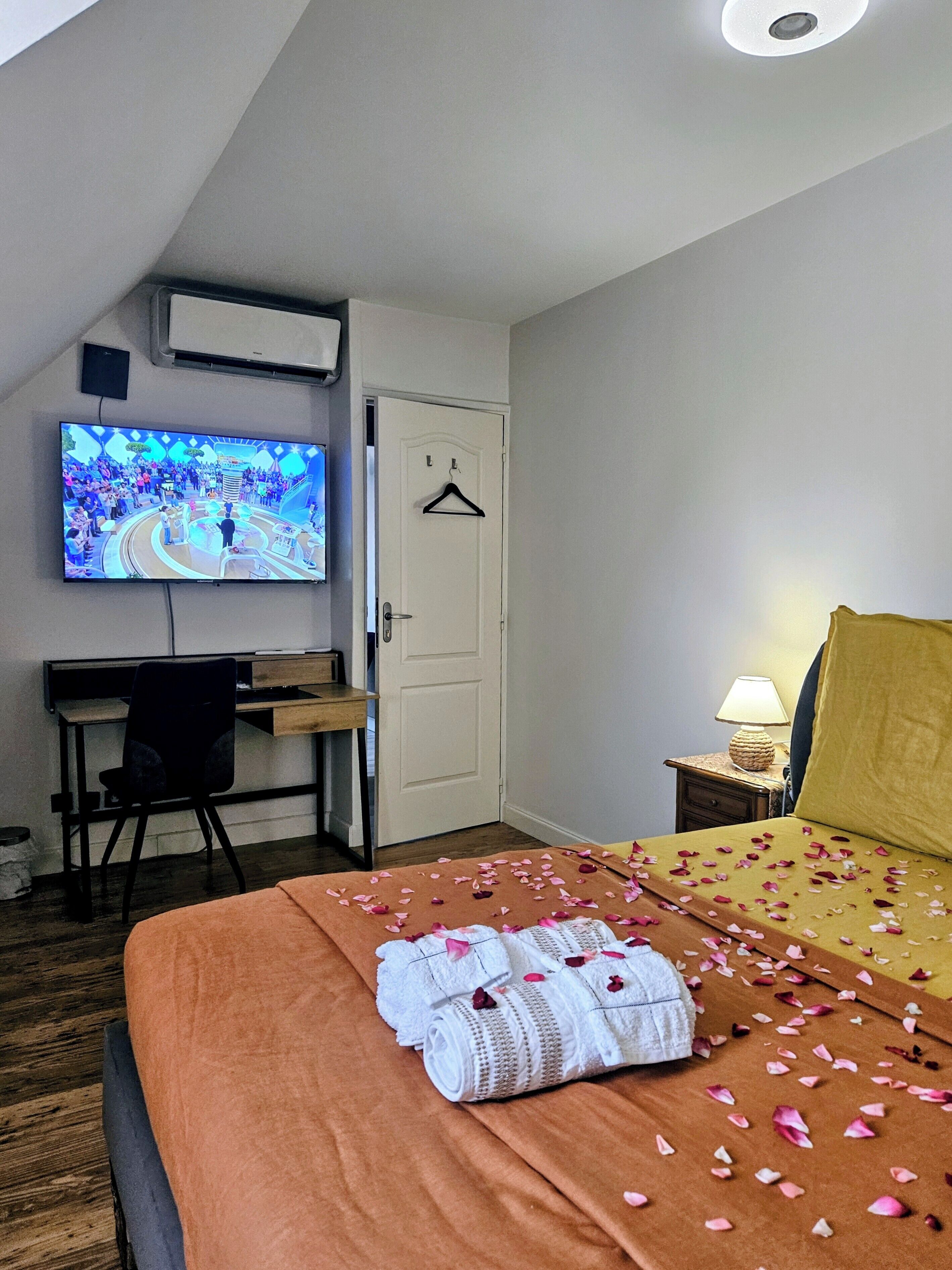 Een hotelkamer met een bed, bureau, televisie en een deur.