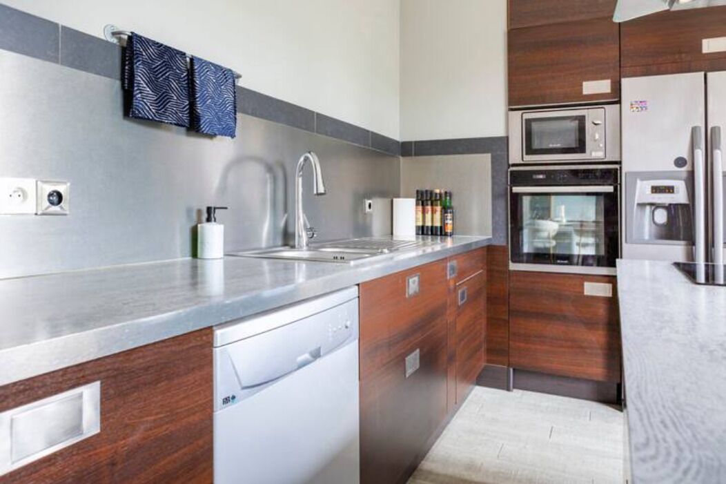 Una cocina moderna con un lavamanos de acero inoxidable, horno empotrado y microondas.