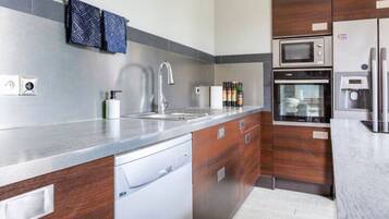 Una cocina moderna con un lavamanos de acero inoxidable, horno empotrado y microondas.
