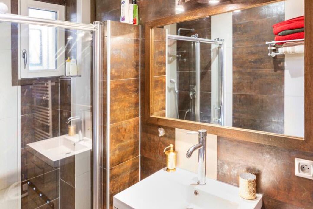 Une salle de bain moderne avec une douche à parois de verre, un lavabo blanc et un grand miroir.