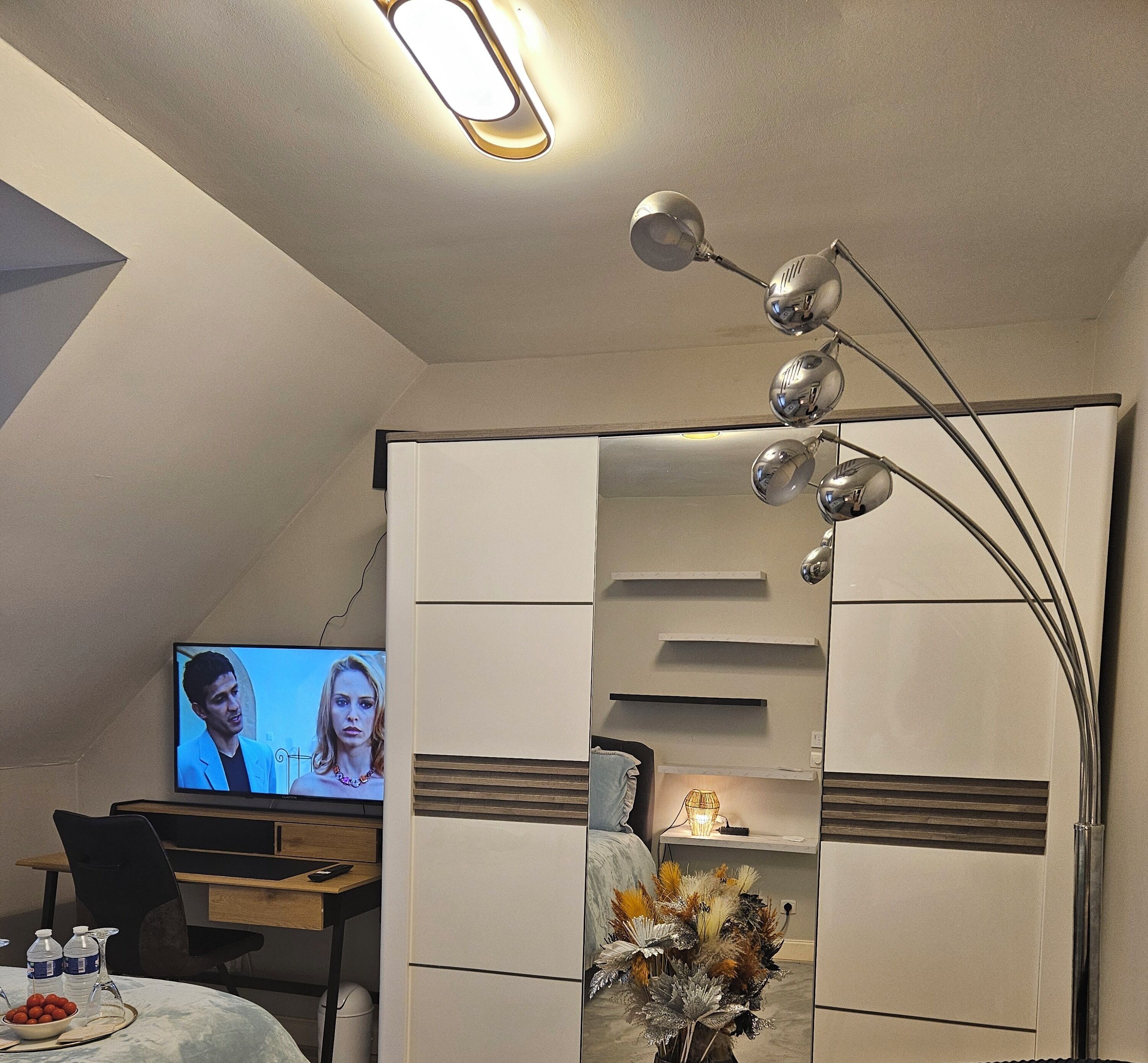 A modern bedroom with a TV, a desk, and a decorative lamp.