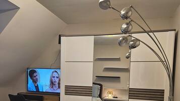 A modern bedroom with a TV, a desk, and a decorative lamp.