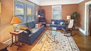 Ein Wohnzimmer mit einem blauen Sofa, einem Holztisch und einem gemusterten Teppich.