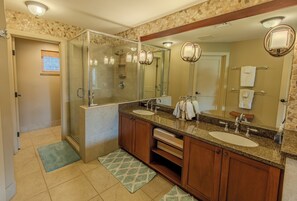A bathroom with two sinks, a large mirror, and a glass-enclosed shower. - Experience Stunning Views from Your Island-Style Suite w/ Kitchen & Living Area (Hawaii County)