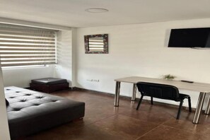 Un dormitorio moderno con cama, escritorio y televisor.