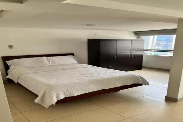 Un dormitorio con cama, armario y ventana.