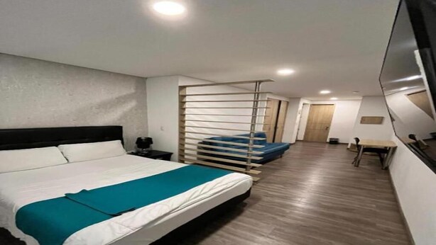 Une chambre d’hôtel avec un lit, un bureau, une chaise et un téléviseur.