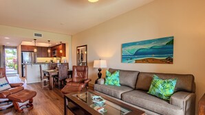 Een woonkamer met een bank, fauteuils, een salontafel en een schilderij van een strandgezicht.