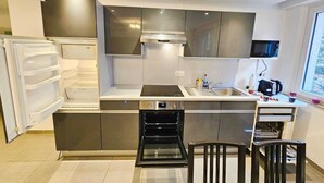 A compact kitchen with a built-in oven, microwave, and sink. There is a small dining area with a chair and a table. - Exceptional 1BR Apartment in center (Luxembourg City)