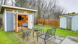 Een kleine, open keuken met een eethoek, een houten terras en een omheinde achtertuin.