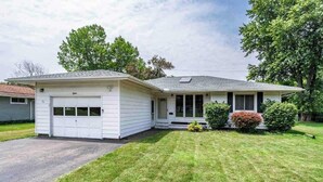 A single-story house with a garage, a covered porch, and a well-maintained lawn. - Enjoyable Home by Airport and Dwtn (Rochester)