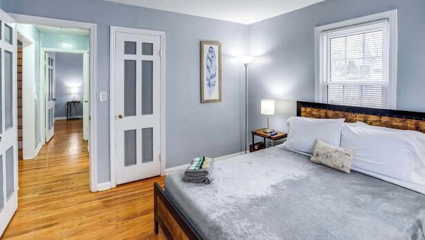 Ein Schlafzimmer mit einem Bett, einem Nachttisch, einer Lampe und einem gerahmten Bild an der Wand.