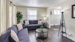 Ein Wohnzimmer mit einem dunkelgrauen Sofa, einem runden Couchtisch und einer Stehlampe.