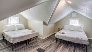 Ein Schlafzimmer mit zwei Betten, Holzboden und schrägen Wänden.