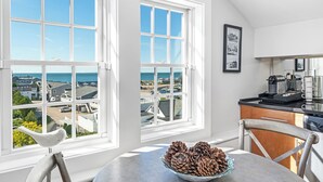 A kitchen with a view of the sea, a coffee machine, and a bird sculpture on the windowsill. - The Eagle’s Nest Penthouse: 360° Views in the Heart of Watch Hill (Westerly)