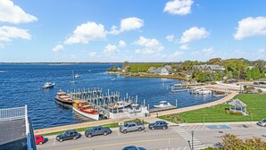 A marina with boats docked, a parking area, and a view of the water and distant shoreline. - The Eagle’s Nest Penthouse: 360° Views in the Heart of Watch Hill (Westerly)