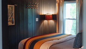 Ein Zimmer mit einem Bett, einem Schreibtisch, einer Lampe und einem fenster mit Vorhängen.
