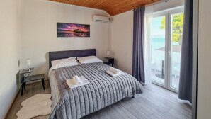 Una camera da letto con un letto, un comodino, un climatizzatore, un quadro e vista sull'esterno.