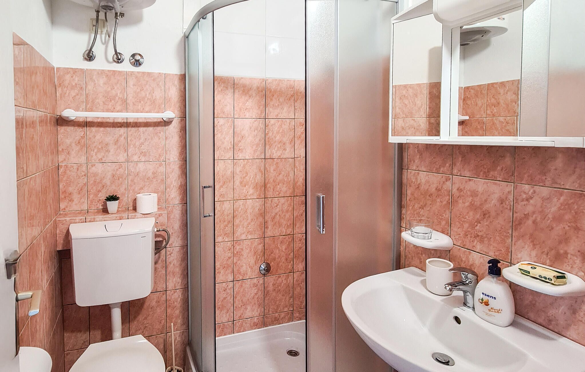 A bathroom with a toilet, sink, and shower area.