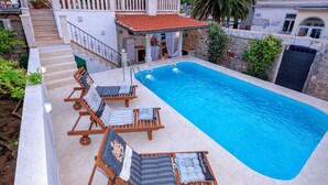 Piscina com espreguiçadeiras e parede de pedra.