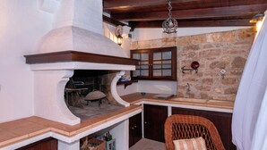 Cozinha com parede de pedra, forno embutido, armários de madeira e uma cadeira de vime.