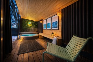 Una terraza de madera con un jacuzzi, un banco y una silla.