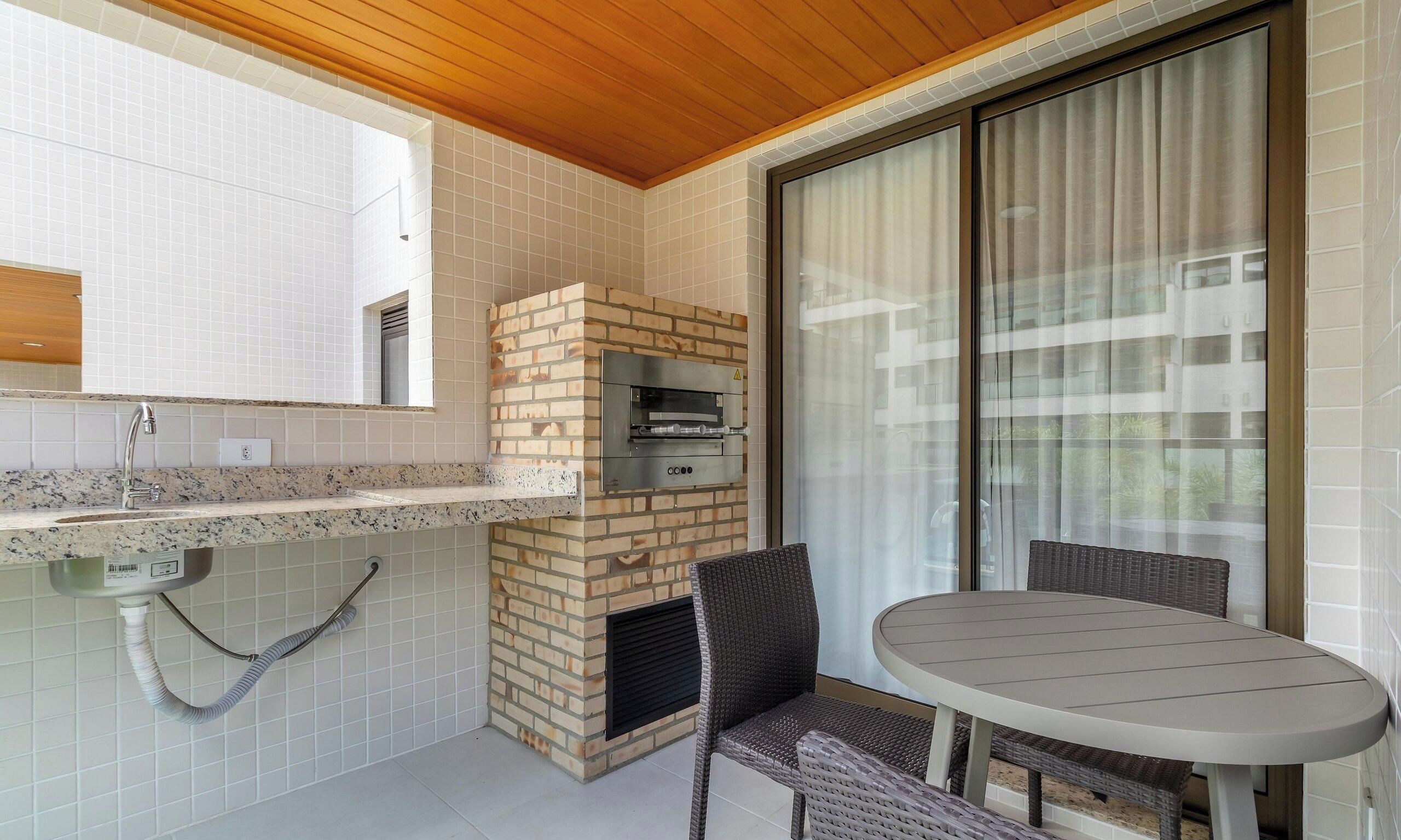 A balcony with a brick oven, a table, and chairs.