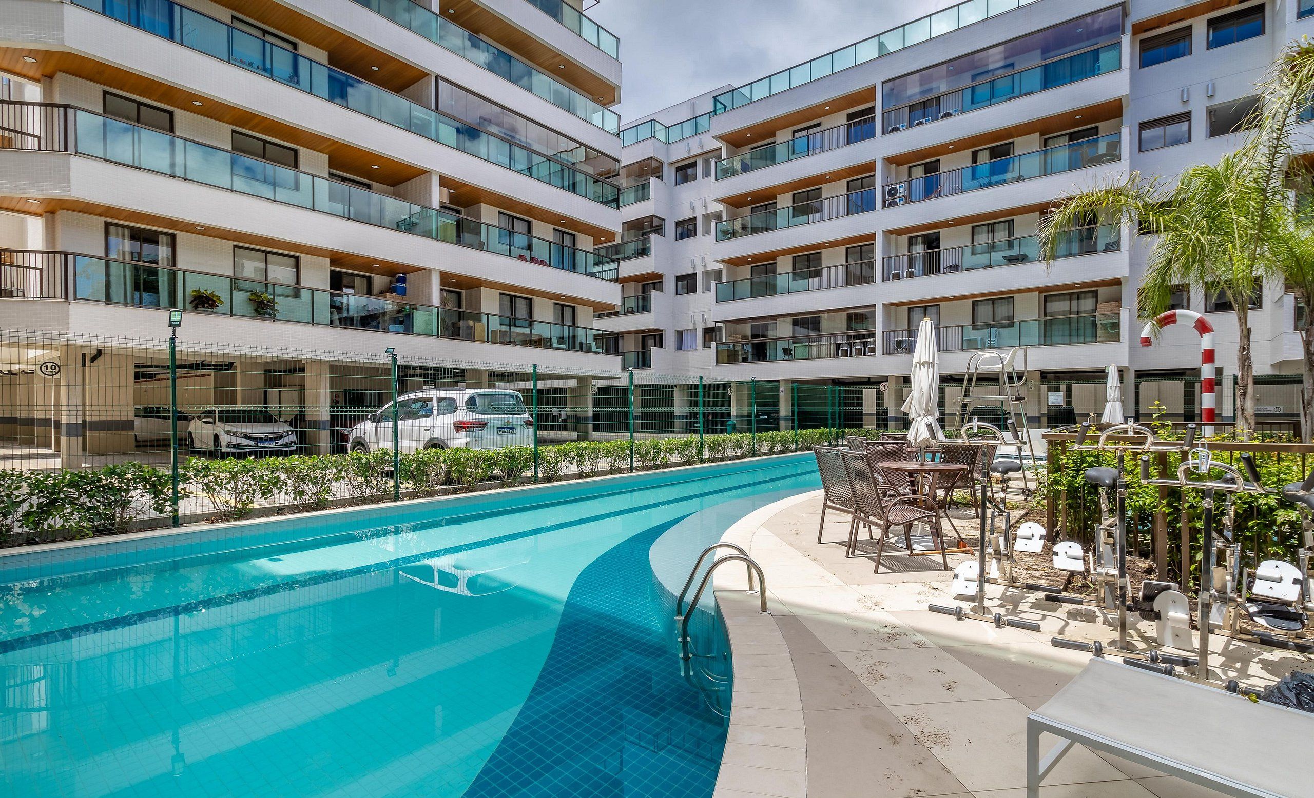 Een modern hotel met een zwembad, terras en meerdere balkons.