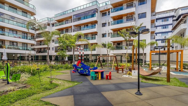 A modern apartment complex with multiple balconies, outdoor seating areas, and a playground. - Apt w/ Balcony, BBQ & Pool View Ano0209 (Cabo Frio)