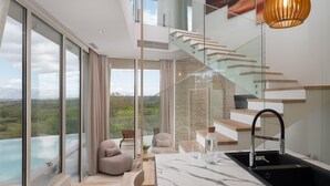 Eine moderne Küche mit Marmorarbeitsplatte, einem schwarzen Spülbecken und einer gläsernen Wendeltreppe, die zu einer oberen Ebene führt.