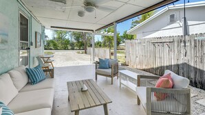 Eine überdachte Terrasse im Freien mit einer Couch, einem Tisch und einem Stuhl.