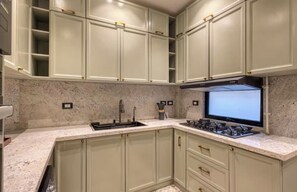 A kitchen with light-colored cabinets, a granite countertop, a gas stove, and a range hood. - Retro Oasis in the Heart of Downtown Cairo (Cairo Governorate)