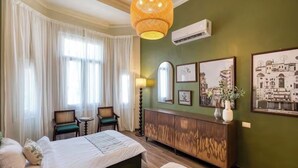 Ein Hotelzimmer mit einem großen Bett, zwei Stühlen, einem Holzschrank und gerahmten Bildern an der Wand.