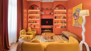 Ein Wohnzimmer mit Kamin, Bücherregalen, einem Fernseher und gelber Möbel.