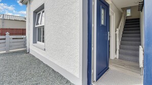 A white building with a blue door, a window, and a staircase leading to an upper floor. - The Wee House - Fáilte Ireland Quality Assured (Muff)