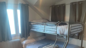 A bunk bed with a sofa and a table in a room with a tiled floor and a ceiling light. - Sierra Nevada Study (Sierra Nevada)