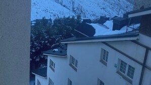 Lumipeitteisen vuoristonäkymä rakennuksesta, jossa on useita ikkunoita ja parveke.