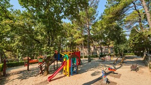A playground with various play structures, including slides and swings, surrounded by trees and a building in the background. - 1 bedroom gorgeous apartment in Porec (Porec)
