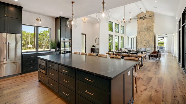 A spacious kitchen with a large island, dark cabinetry, and modern lighting fixtures. - Ledgestone Ranch - Luxury Ranch - Pickleball - Bocce - Pool - Firepit (Wimberley)