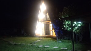 A modern, triangular-shaped building with a well-lit entrance and a pathway leading to it. - Casa de campo y chalet las morenas  (Sicuani)