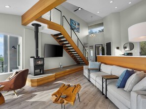 A modern living room with a wooden staircase, a fireplace, a sofa, and a dining area. - Ocean View Getaway (Manchester)