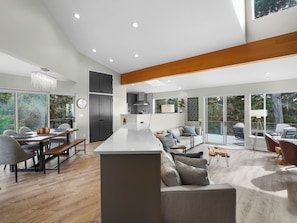 A modern kitchen with a central island, dining area with chairs and a bench, and a living area with a sofa and coffee table. - Ocean View Getaway (Manchester)