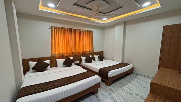 Habitación de hotel con dos camas, cabecera de madera, ventilador de techo, iluminación empotrada y suelo de mármol.