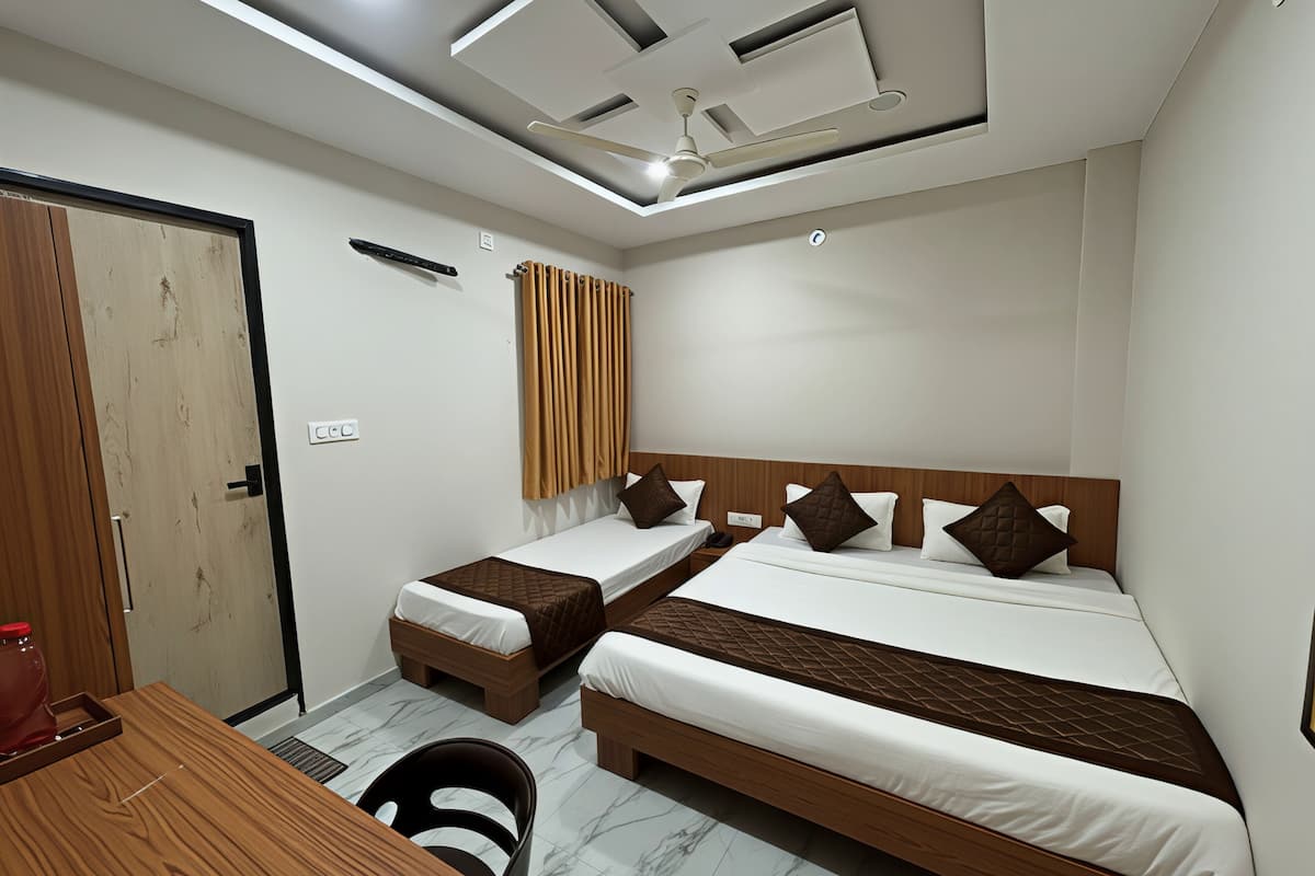 Habitación de hotel con dos camas individuales, un escritorio de madera, una silla, un radiador y un ventilador de techo.