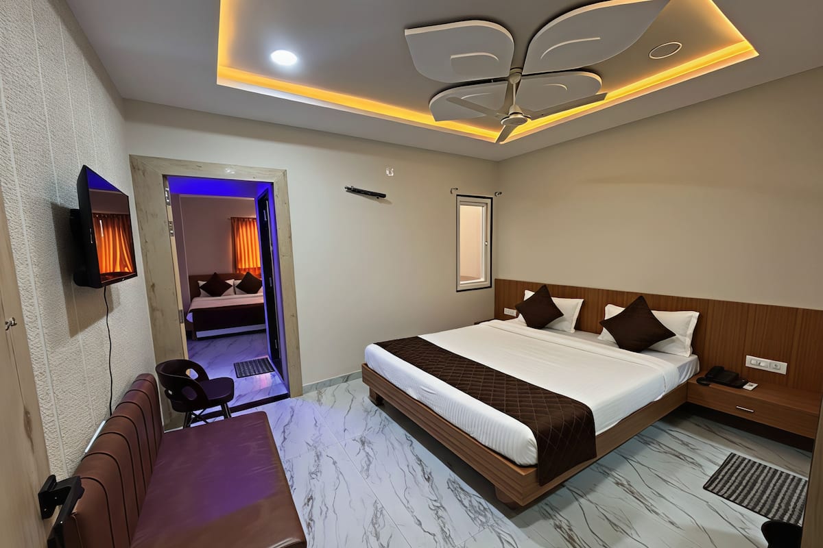 Una habitación de hotel moderna con una cama grande, un escritorio, una silla y un televisor montado en la pared.
